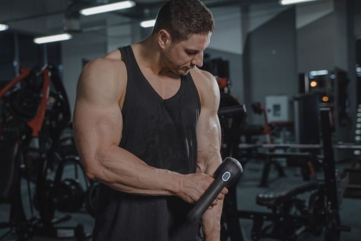 Athlete using a massage gun after a workout
